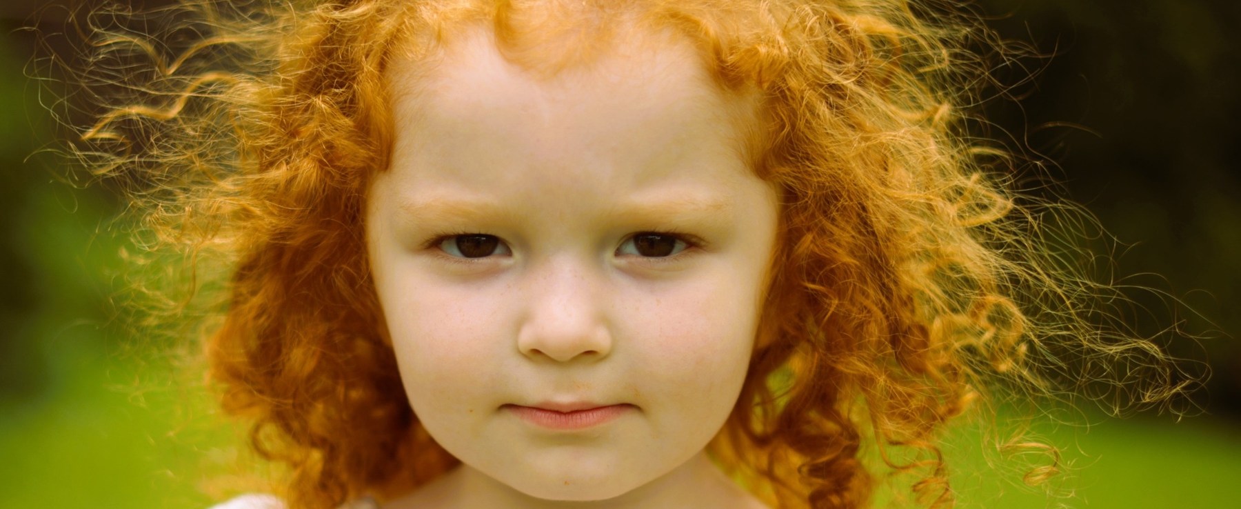 Close-up outdoor portrait of a young child with curly red hair in Northern Kentucky