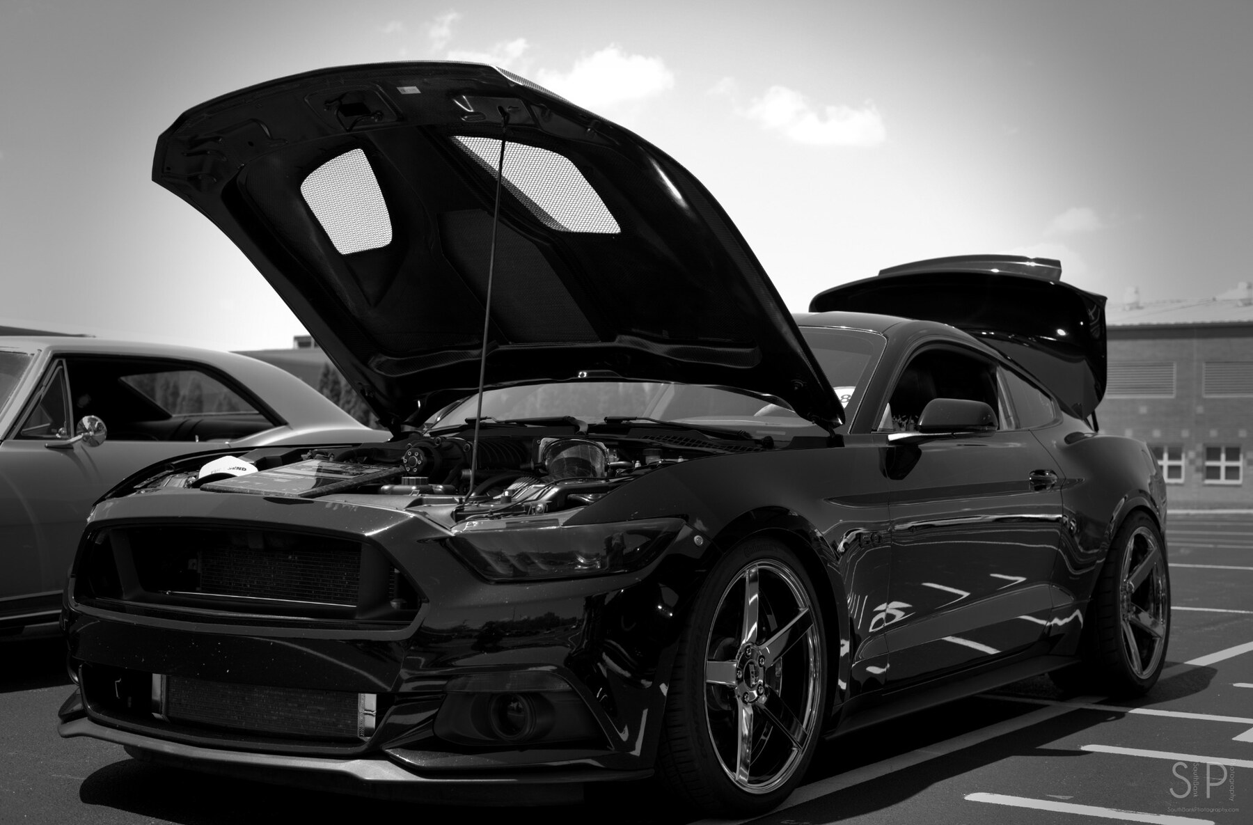 Black and white view of a black Ford Mustang with its hood open