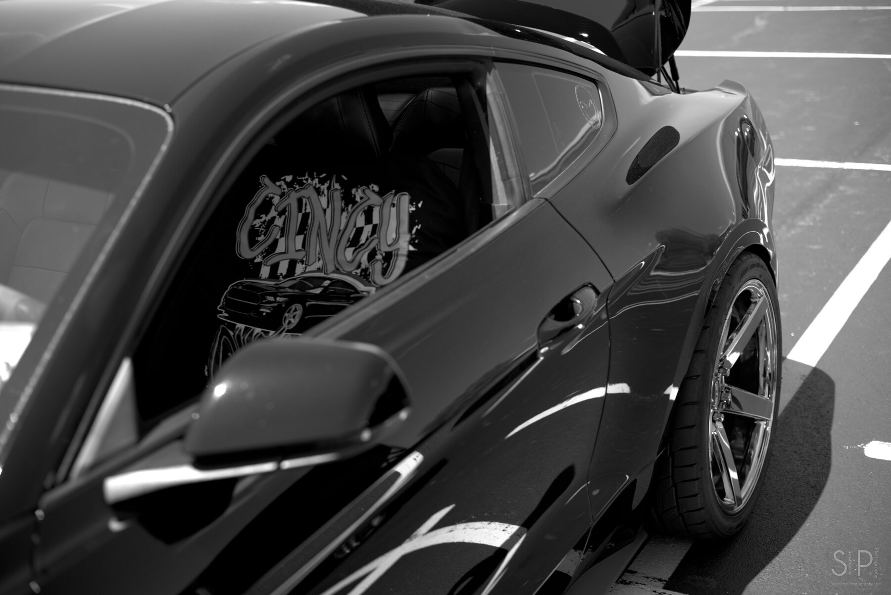 Black and white detail of a custom Mustang quarter window and rear wheel
