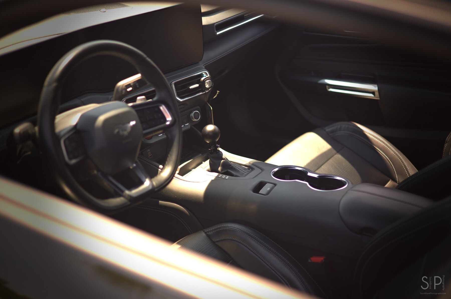 Warm-toned view of a manual-transmission Ford Mustang interior