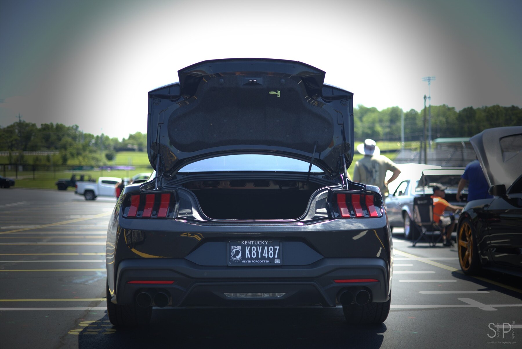 Rear view of a gray Ford Mustang with its trunk open at a car show