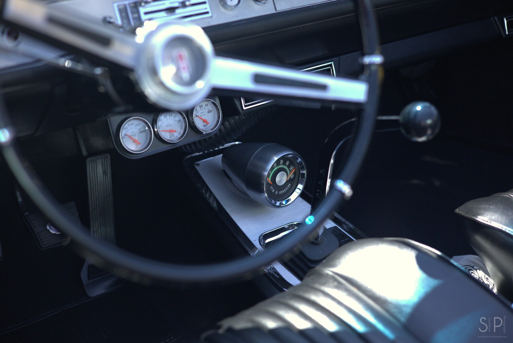Vintage steering wheel and aftermarket gauges inside a classic Oldsmobile 442