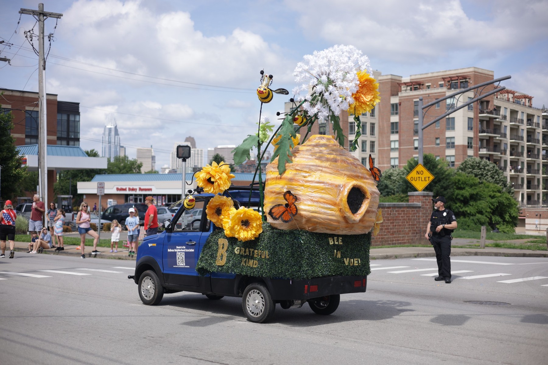Bee-themed community parade float with the Cincinnati skyline in the distance