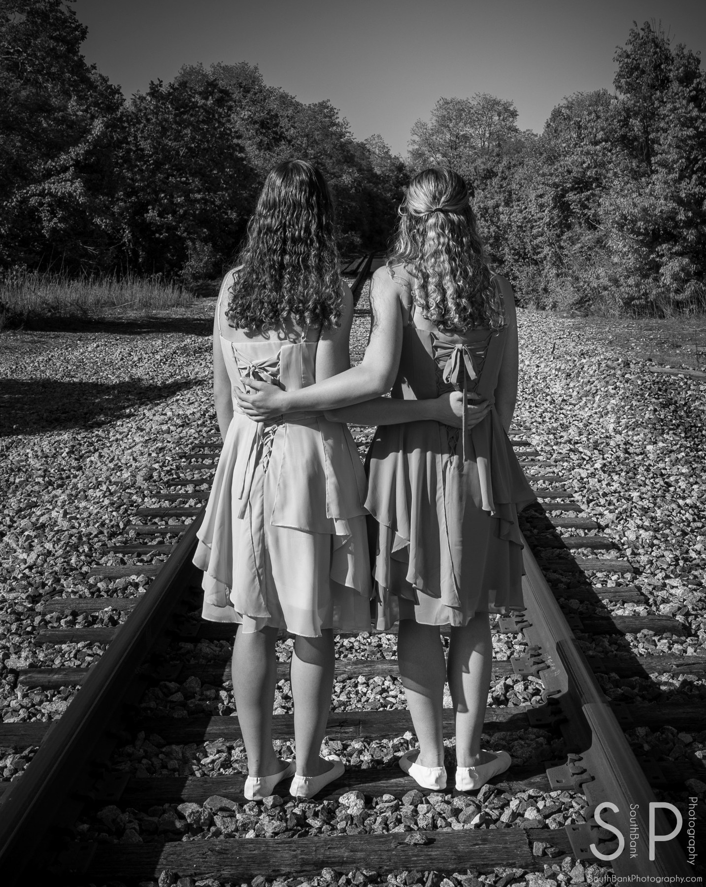 Black and white portrait of two people standing together on railroad tracks