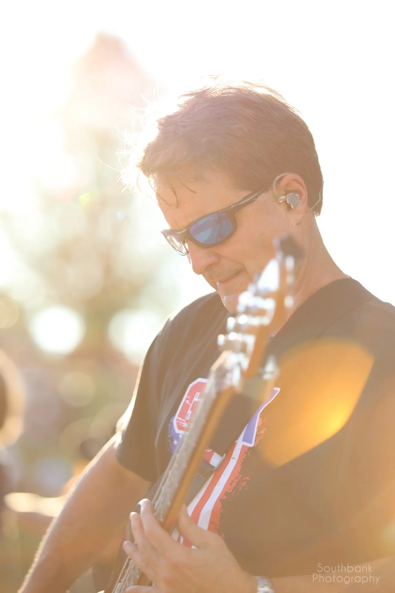 Bass guitarist backlit by late-day sunlight during the GenX concert