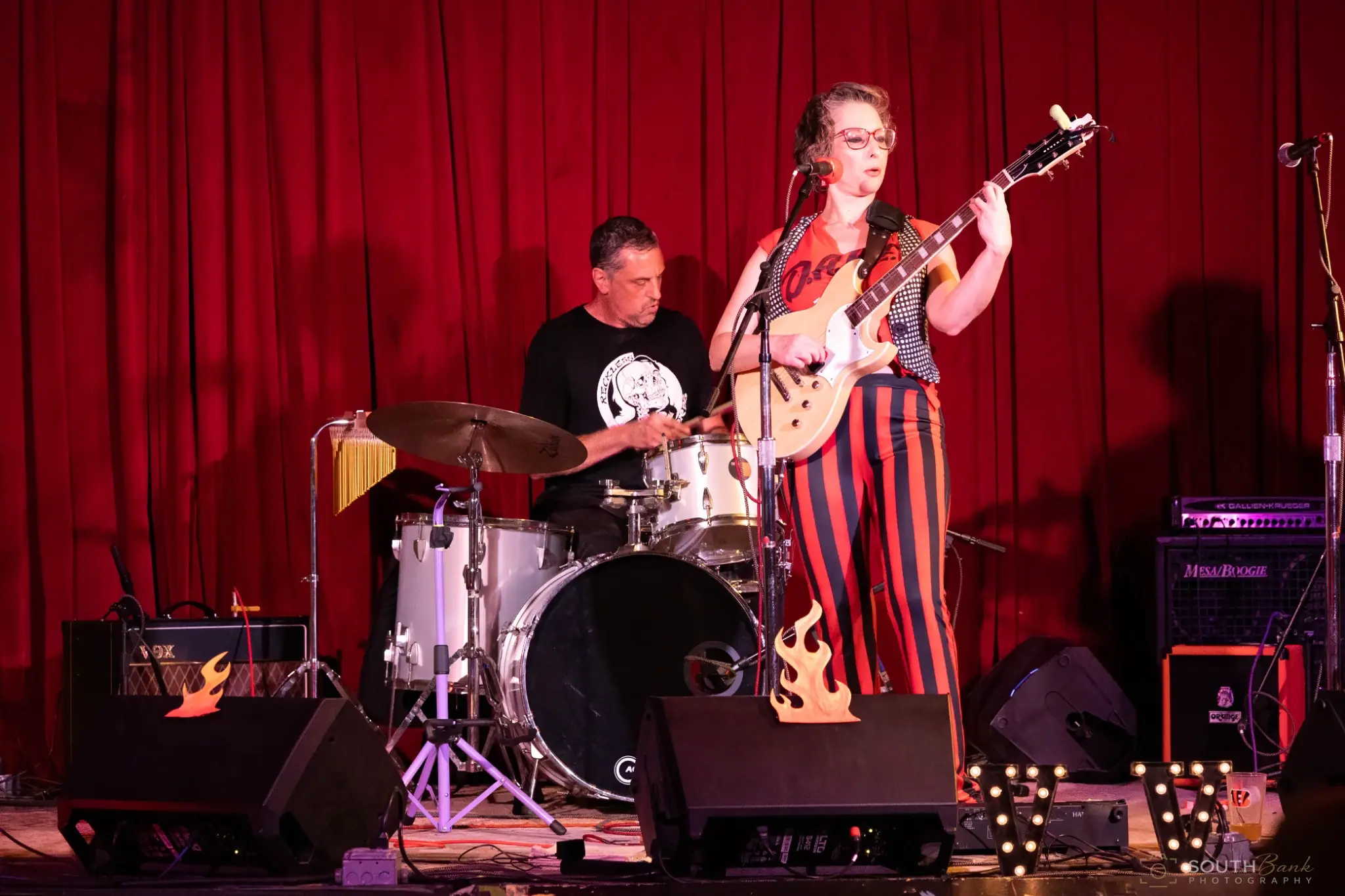 Guitarist and drummer performing in a live music venue
