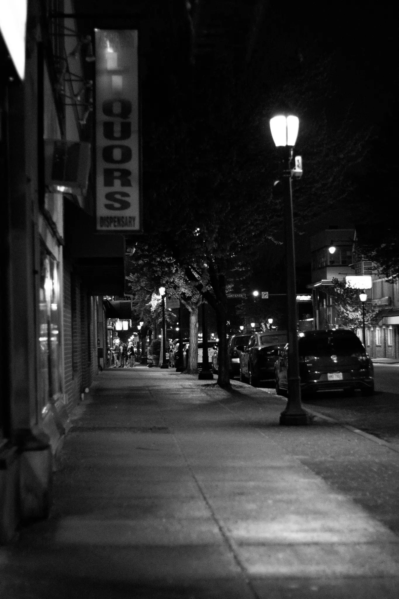 Black-and-white view down a quiet commercial street at night